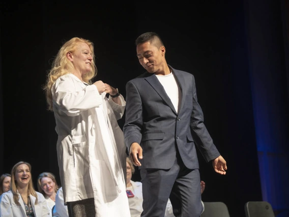 Professor Kristie Hoch presents Sebastian Maderazo with his coat during the College of Nursing’s Doctor of Nursing Practice white coat ceremony.