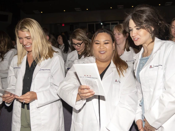 Newly coated Doctor of Nursing Practice students Isabell Diamond Allen, Nicole Renee Escobar and Leah Gawin-Maakestad recite the student oath of responsibility.