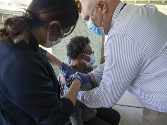 First-year College of Medicine – Phoenix student Bernice Alcanzo gives a COVID-19 vaccine to Alice Scott, resident service coordinator at El Mirage Senior Village, as Dr. Jim Lindgren assists.