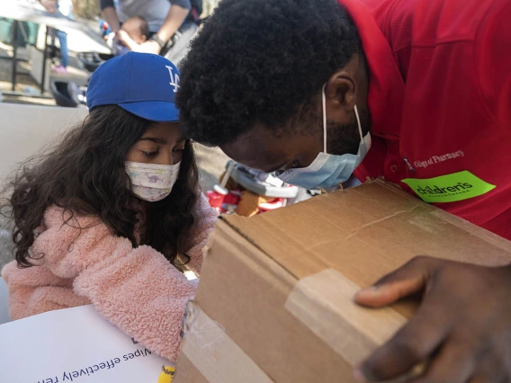 Vanessa Rendon places her hand in a box to see what germs are on her skin as University of Arizona R. Ken Coit College of Pharmacy student Anyang Ndobegang shines a black light on her hands during the recent Family SciFest at Children's Museum Tucson.