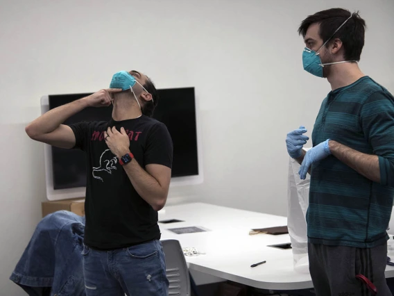 Second-year College of Medicine – Tucson student Alexandre Cavalcante adjusts his N95 mask as student-volunteer Billy Evans watches.