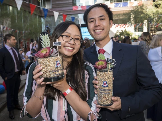 Julie Tran and Diep Nguyen pose for a photo holding each other’s succulent plants that contain their letters before the start of the College of Medicine-Phoenix Match Day 2022 event.