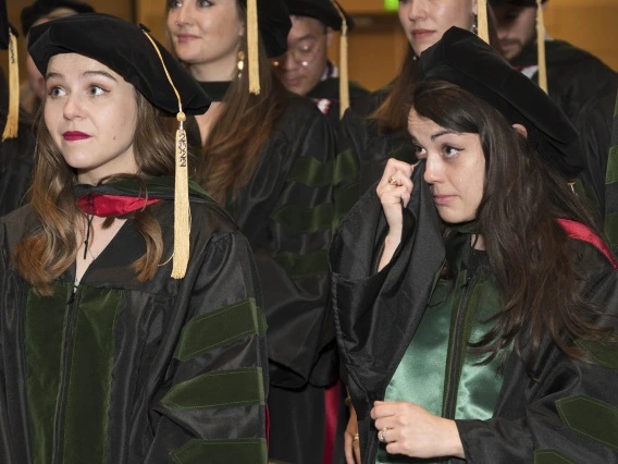 Nicole Deatherage, MD, (front right) wipes a tear from her eye with her graduation gown as she and Merrion Dawson, MD, (left front) listen to speakers during the College of Medicine – Phoenix class of 2022 commencement ceremony.  