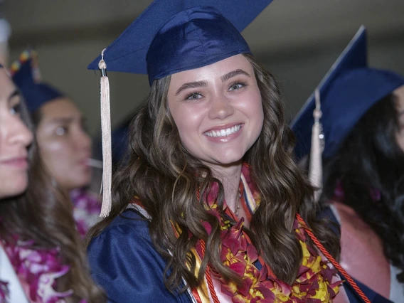 Edda Anderson wears a graduation lei with the traditional cap and gown as she waits to cross the Centennial Hall stage to receive a bachelor’s degree at the 2022 Mel and Enid Zuckerman College of Public Health spring convocation.