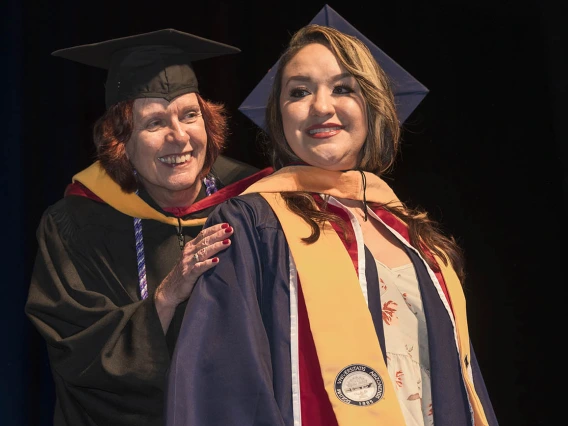 College of Nursing senior lecturer Kathleen Malkin, MSN, hoods Stephanie Figueroa, who earned a master’s degree in nursing clinical systems leadership, during the College of Nursing 2022 summer convocation.