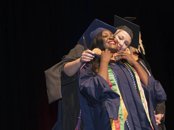 Master of Science in Nursing Entry to the Profession student Rosine Laure Bouguem is hooded by Carrie Van Bakel, MSN, during the College of Nursing’s 2022 summer convocation.