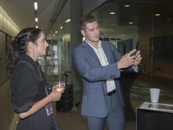 (From left) Nicole Jimenez watches as Zackary Sabetta, a neurotrauma research technician in the College of Medicine – Phoenix, shows the augmented reality artwork created by artist Rembrandt Quiballo titled “It’s All in Your Head—Deconstructing the Brain Concussion” during the public opening of Artist + Researcher exhibition.