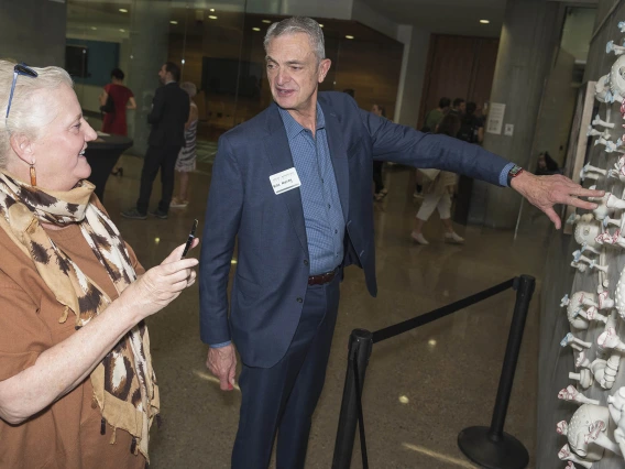 Michael Murray, MD, PhD, MCCM, a professor of anesthesiology and internal medicine in the College of Medicine – Phoenix, tells his wife, Cate Murray, about the ceramic piece artist Danielle Wood created based on his research during the public opening of the Artist + Researcher exhibition at the Health Sciences Education Building on the Phoenix Biosciences Core.