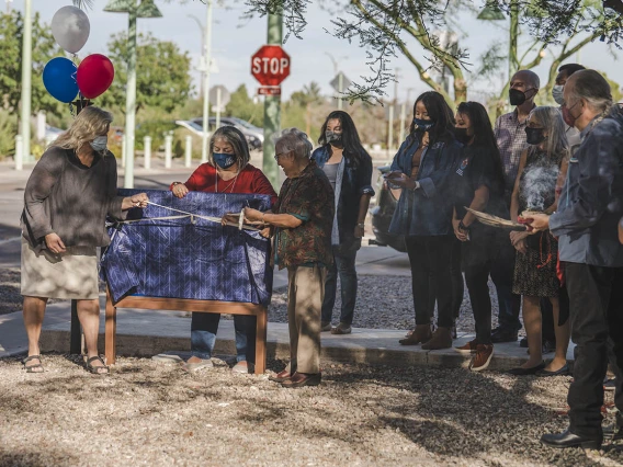 Ann Mathias, DO, interim chair, vice chair for clinical affairs, clinical assistant professor (left) and Jennie Joe, PhD, MPH, professor emerita, Family and Community Medicine, prepare to remove the covering over the new signage during the renaming ceremony for the Wassaja Carlos Montezuma Center for Native American Health.