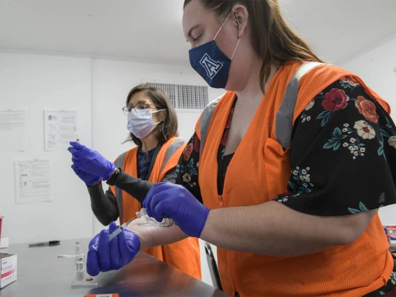 UArizona Campus Health registered pharmacist Elizabeth Preble (left), and fourth-year College of Pharmacy student Annie Hiller prepare to mix the Pfizer vaccine with saline.