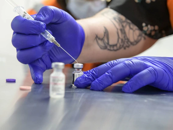 Hiller is shown mixing the contents of a Pfizer vaccine with a saline solution to get it ready for recipients. 