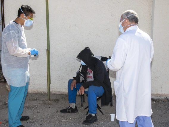 Medical student Christian Bergman (left) and Z Mansion owner Tom Hill (right) speak with an individual at Tucson’s Z Mansion downtown soup kitchen. Bergman and other medical students are helping provide health care services to this vulnerable population.