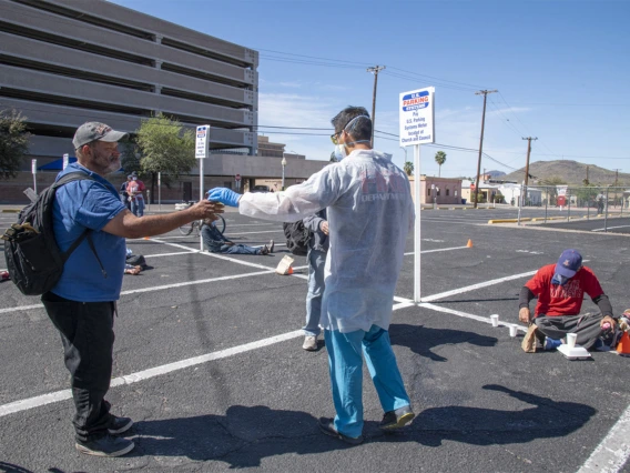 Christian Bergman hands out beverages at Tucson’s Z Mansion soup kitchen. He and other medical students are volunteering to provide health care services to the vulnerable homeless population.