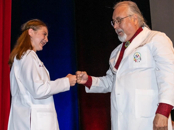 Jordan Gotwalt gets a fist bump from Dr. Carlos Gonzales after he presented her with her white coat. 