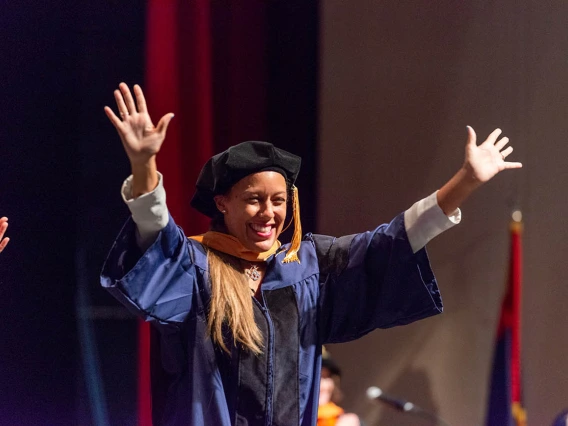 Minci Sekou Stenson, who earned a Doctor of Nursing Practice, waves to the audience after being hooded at the College of Nursing convocation at Centennial Hall in December.