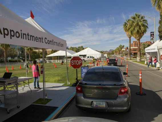 A volunteer confirms appointments as people arrive at the COVID 19 drive-through vaccine distribution site on the University of Arizona mall.