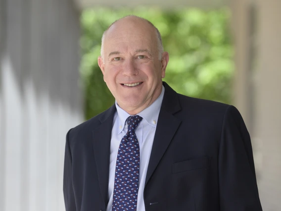 Portrait of Dr. Abraham, a older bald man wearing a dark suite and tie. 