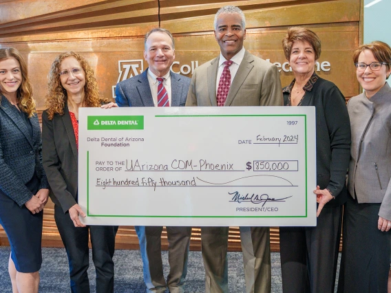 group of people holding oversized presentation check for $850,000