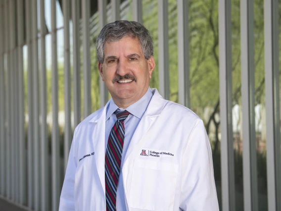 Portrait of man wearing a blue dress shirt and stripped blue and red tie standing outside of a building.