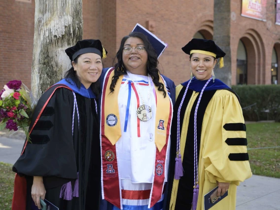 Two U of A College of Nursing faculty members pose with a graduating student after the college’s convocation ceremony.