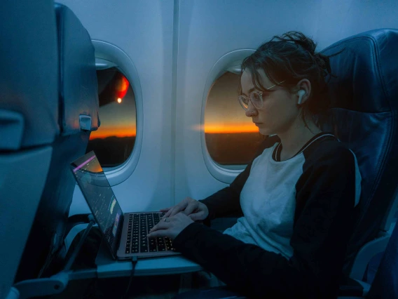 Passenger on plane working on laptop at daybreak 