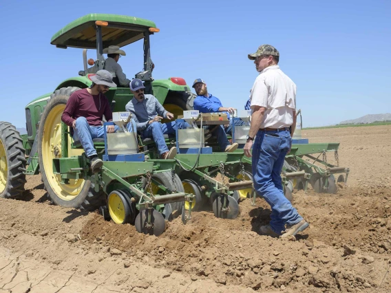 people planting tepary beans using a tractor and row crop planting machinery   