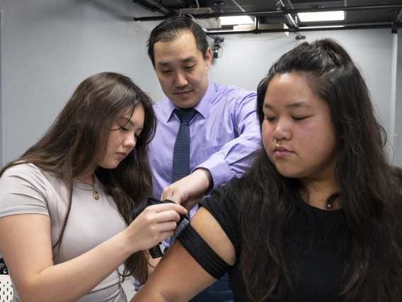 Jonathan Lee-Confer assists a student putting an arm sensor on another student.