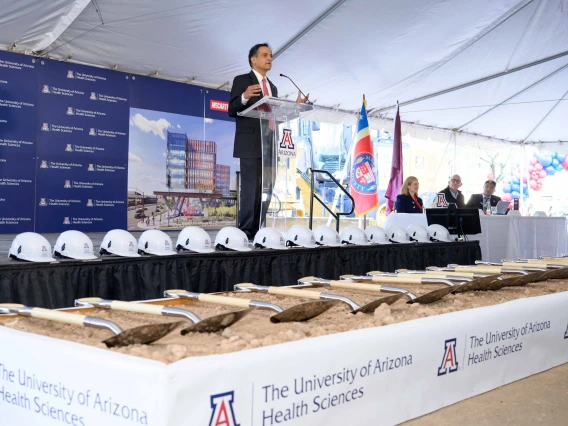 University of Arizona President Suresh Garimella stands on a stage with hard hats, shovels and dirt at his feet. 