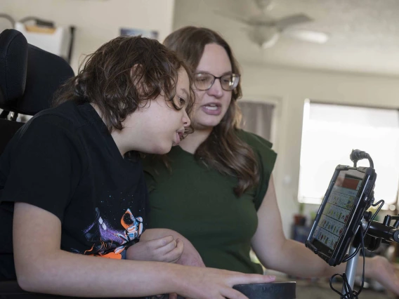 Mother and son in wheelchair looking at screen communication device