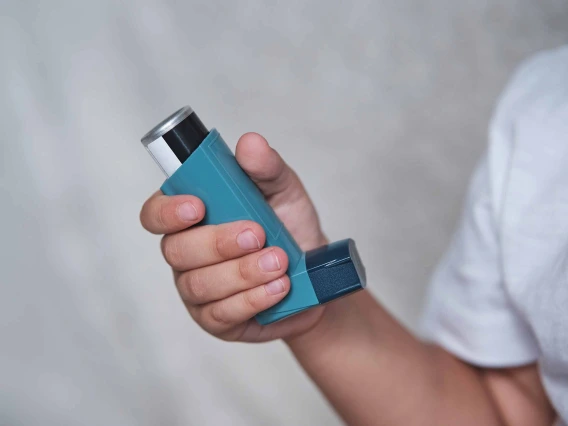 A person holds a blue asthma inhaler