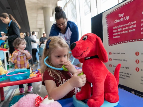 Little girl gives stuffed animal a check-up at the Wildcat Play Hospital sponsored by the University of Arizona College of Nursing.