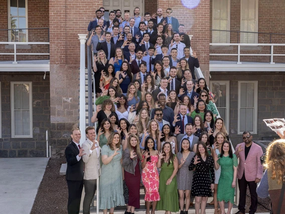  A large group of medical students stands on the stairs of an old building. 