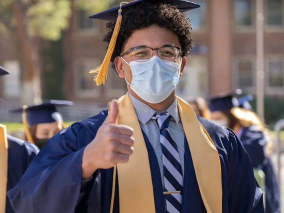 College of Nursing student Isaiah Buster signals that he is ready for the College of Nursing’s fall convocation as he walks into Centennial Hall.