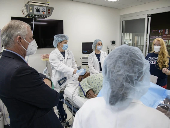 Kristie Hoch, DNP, CRNA, MS, RRT, (right) program administrator for the CRNA class, talks with her students and University of Arizona President Robert C. Robbins, MD, during a debriefing after the completion of their simulation. 