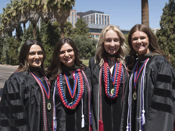 Hannah Muasher, PharmD, Sydni Martinez, PharmD, Lauren Kimsza, PharmD, and Sammantha Meyer, PharmD, pose for a photo outside Centennial Hall after the R. Ken Coit College of Pharmacy 2022 spring convocation at Centennial Hall.