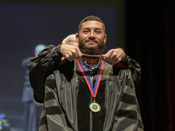 Andy Valencia, PharmD, is hooded by John Regan, PhD, during convocation for earning his Doctor of Pharmacy during the R. Ken Coit College of Pharmacy 2022 spring convocation at Centennial Hall.