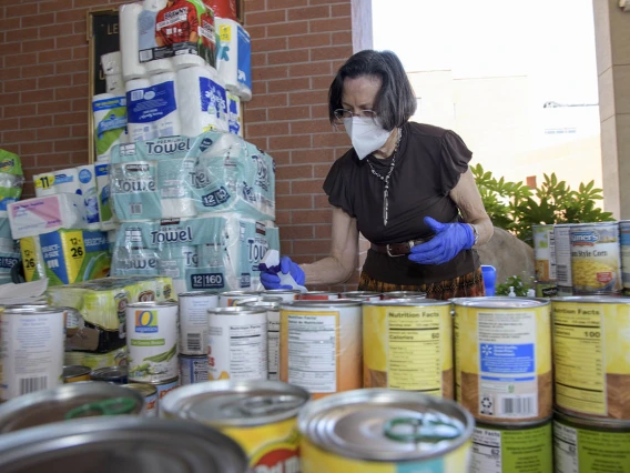 Margaret Briehl, PhD, principal investigator for the Partnership for Native American Cancer Prevention at the University of Arizona Cancer Center, sanitizes donations. The Cancer Center donation drive she helped spearhead brought in 1,384 single-use bottles of water, 57 gallons of water, 260 cans of corn, 113 cans of peaches, 60 cans of other fruits and vegetables, 12 cartons of almond milk, 2 large containers of rice, 451 rolls of paper towels, 53 rolls of toilet paper, 21 packages of napkins, 50 bottles o