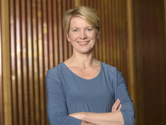 Woman with short blond hair wearing a blue blouse and arms folded