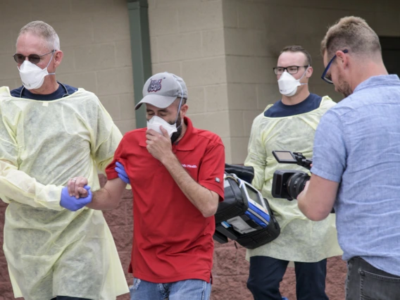 The Mel and Enid Zuckerman College of Public Health worked with Tucson Fire Department and the Western Regional Public Health Training Center to produce a training video for first responders on COVID-19 emergency calls in early March. Erich Healy, right, films as Tucson Fire Department’s Chris LaFave, left, helps guide Jonathan Sexton, PhD, who is playing a possible COVID-19 patient in a training video, into an ambulance.