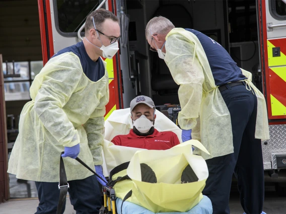 Firefighters Taylor Parrish and Chris LaFave wrap Jonathan Sexton, PhD, in a protective barrier to demonstrate how to prevent further spread of a virus during an ambulance trip to the hospital.