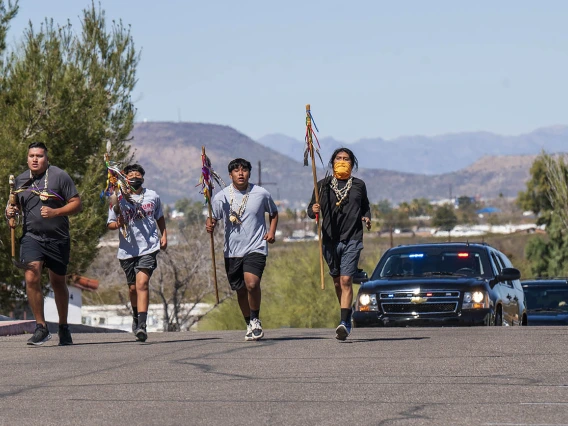 Four cultural runners escort first lady Jill Biden's motorcade onto the Tohono O'odham Nation during a visit to the San Xavier Health Center in the San Xavier District of the Tohono O'odham Nation March 8, 2022.