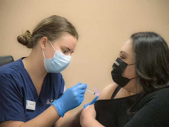 College of Nursing student Valerie Pedersen gives a woman a COVID-19 vaccine at a MOVE UP clinic at the Consulate of Mexico in Douglas hosted by UArizona Health Sciences in partnership with the Cochise County Health Department.