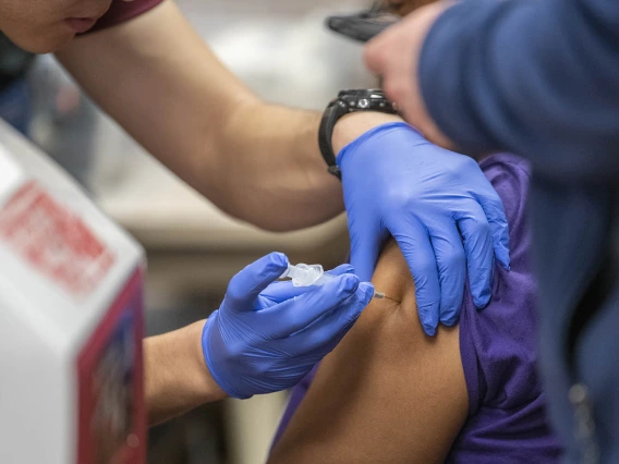 A Street Medicine Phoenix student volunteer administers the flu vaccine to a patient.