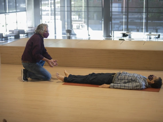 While a participant rests on his back, Andrew Belser demonstrates a technique to promote mindful movement during the second class in the “Aging and the Arts” series.