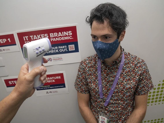 Graduate student Gregory Branigan receives a temperature check outside of the Center for Innovation in Brain Science at Bioscience Research Laboratories. The center implemented COVID-19 screening with daily online health surveys and temperature scans for all faculty, staff and students entering buildings.