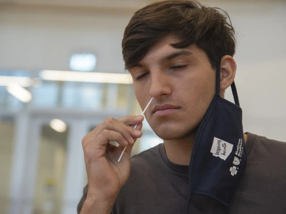 University of Arizona student Heath Zuniga inserts a nasal swab into his nose. The COVID-19 test was required for all dormitory residents prior to moving in to their dorms in August, and remains available to students and staff.