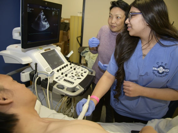 A high school student practices performing an ultrasound on a human heart.