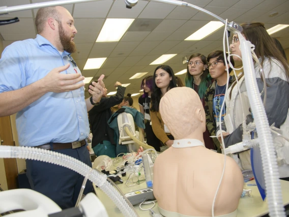 High school students learning about career options in health care gather around the respiratory station.