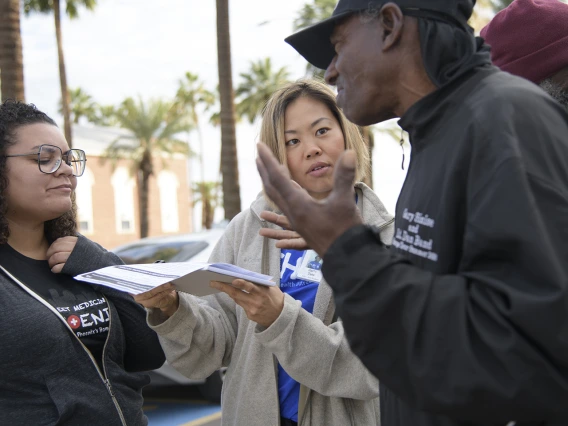 Street Medicine Phoenix volunteers help a patient complete an assessment form outside of Grace Lutheran Church.