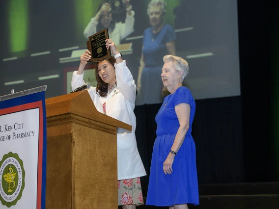 Jeannie K. Lee, PharmD, BCPS, BCGP, FASHP, presents a plaque to guest speaker Metta Lou Henderson, PhD, an alumna, professor of pharmacy emerita and research professor in the Department of Pharmacy Practice at the R. Ken Coit College of Pharmacy. 